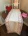 Bring timeless elegance to your Valentine's Day table with this exquisite runner. Set against a pristine white background, an enchanting embroidered border in soft pinks and rich reds creates a romantic focal point that captivates at first glance. The intricate needlework detail adds sophistication and handcrafted charm to your dining experience. Whether you're hosting an intimate dinner or a festive gathering, this stunning piece transforms your table into a declaration of love and impeccable taste that yo