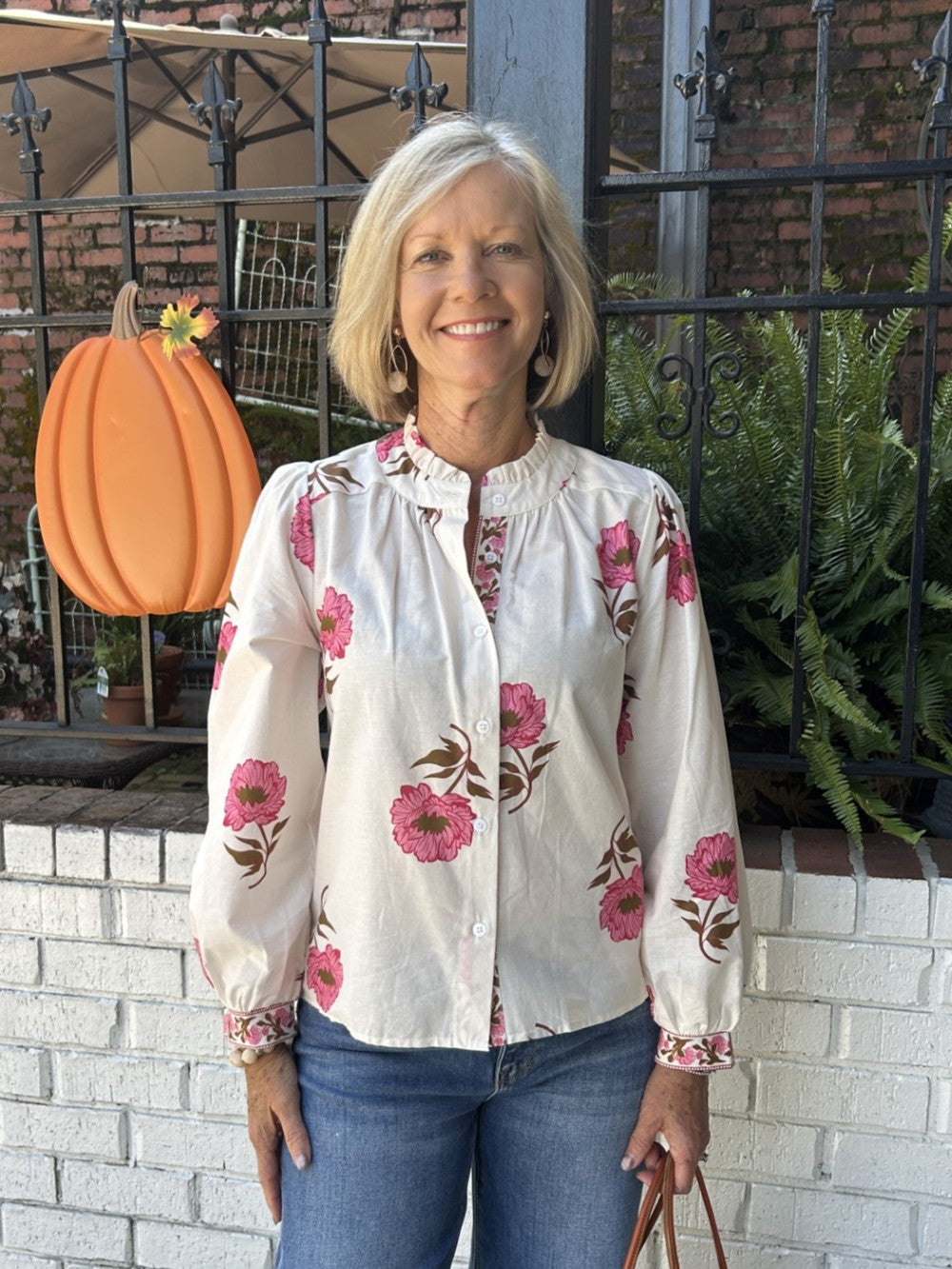 Discover effortless charm in this long sleeve floral print top, featuring a soft cream background with delicate pink florals. The button-up front and ruffled collar add vintage-inspired flair, while floral cuff detailing completes the look. Lightweight, this piece transitions seamlessly from day to night. A timeless wardrobe essential with personality.

Barbara is wearing a size Small.

Material: 100% Cotton

Care Instructions: Gentle cool hand wash, dry flat