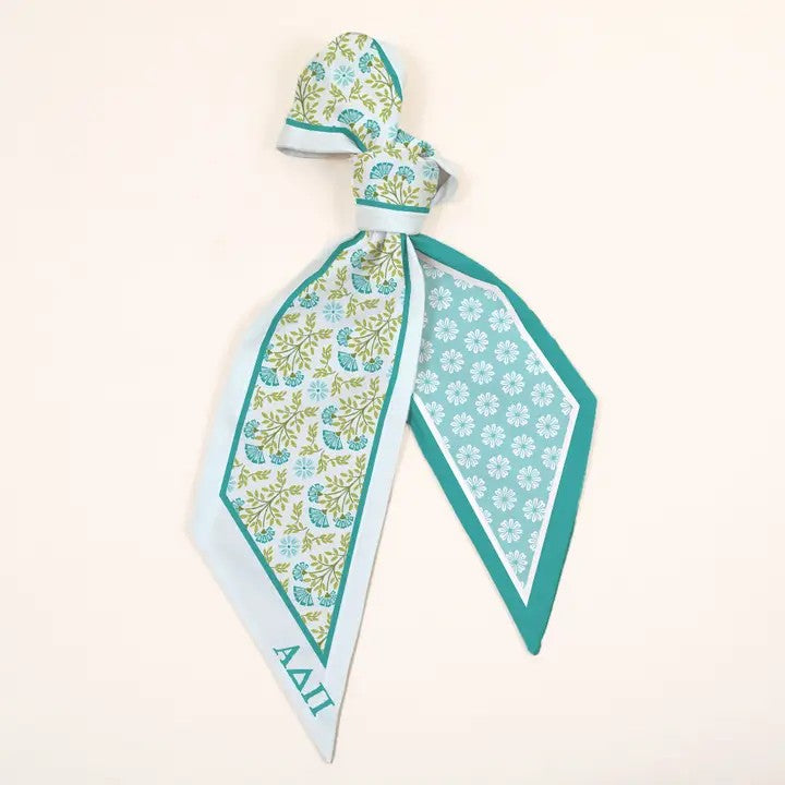 This soft scarf accessory adds a cheerful burst of movement to bags, outfits, or hairstyles. It drapes gracefully and ties with ease, offering endless styling options while featuring your sorority letters. Whether knotted simply or tied in a bow, it brings charm to your day. Versatile and perfect for any occasion. A fun way to show your sorority spirit!

Details:

Satin-smooth fabric allows you to effortlessly elevate any look
Wear in hair, on a purse, around the wrist, or around the neck
Double-sided desig