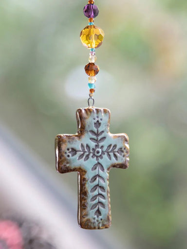 Carry your faith with you wherever the road takes you. This artisan cross car charm is hand-molded with care and features an adjustable length to fit any vehicle. A meaningful reminder of blessings and spiritual protection for daily journeys.

Dimensions: 4.5in L beaded strand, 2.5in L x 1.75in W cross, 12in faux leather strand

Material: Cross: terra cotta, Beads: glass &amp; acrylic