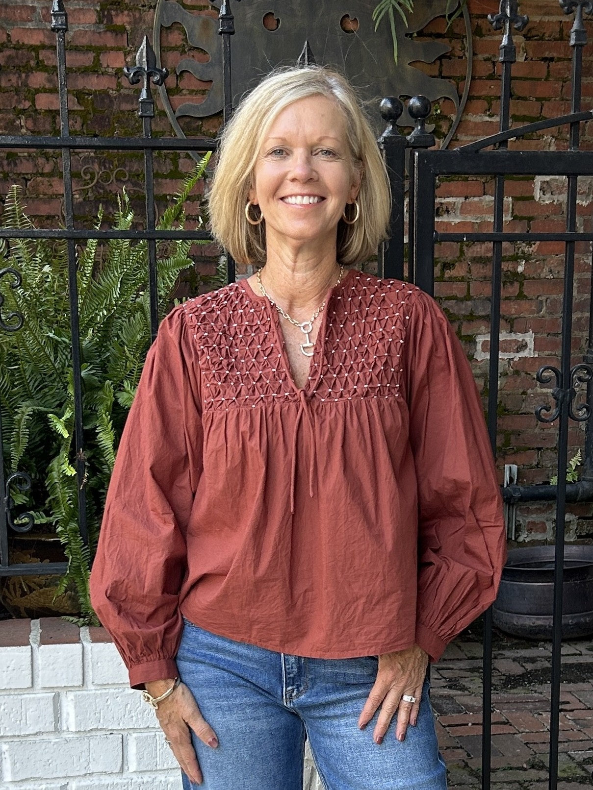 Rust-hued top with intricate front smocking and adjustable tie closure. The perfect layering piece for transitional weather, this design bridges casual and polished styling with refined detailing and an on-trend autumn shade.

Material: 100% Cotton

Care Instructions: Gentle cool hand wash, dry flat