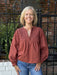 Rust-hued top with intricate front smocking and adjustable tie closure. The perfect layering piece for transitional weather, this design bridges casual and polished styling with refined detailing and an on-trend autumn shade.

Material: 100% Cotton

Care Instructions: Gentle cool hand wash, dry flat