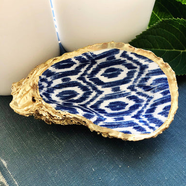This handcrafted Decoupage Oyster Ring Dish is the perfect blend of NC coastal design and charm. Made from a natural oyster shell and decoupaged with a beautiful print, this dish can be used to store small trinkets or simply to add a touch of coastal beauty to your home. The reverse side of the dish is finished with gleaming gold enamel and trim that adds a luxe, eye-catching appeal.  Shells are approximately 3-4.5in long 