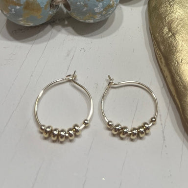 Enhance&nbsp;any outfit with our Callie Hoop Earrings! These delicate wire hoops are beautifully draped with a row of tiny gold beads, giving them a lovely and elegant touch. These stunning and versatile earrings!