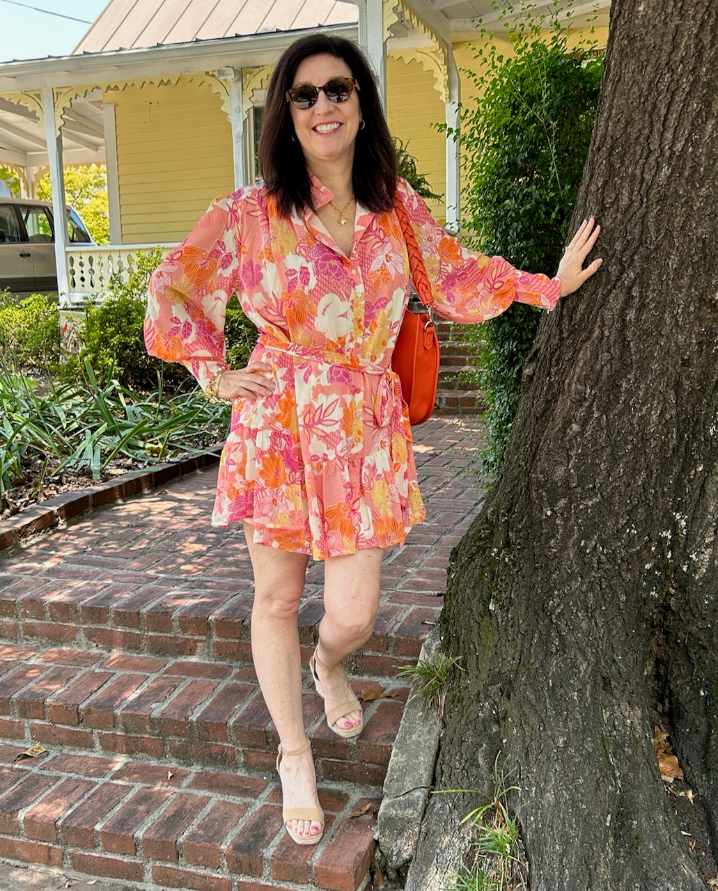 How pretty is this Floral Print Button Front Dress?! We love the color, the fabric, the flirty skirt and the great fit! Though long sleeved, the airy fabric keeps you cooler while covering your arms. It is a beautiful floral print in shades of magenta, orange, yellow, and cream. The button-up front ends at a mock neck offering the opportunity to wear the neck oped, as Tara is, or buttoned closed. The dress is lined and perfect for all occasions. It's certain to brighten you day! 