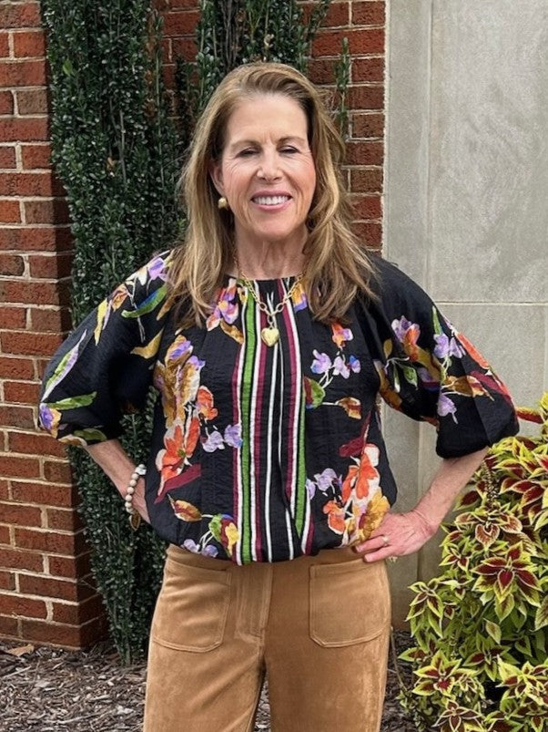 This blouse features a striking black background adorned with vibrant stripes and floral patterns, creating a unique and eye-catching look. Designed with elegant elbow-length puffed sleeves, it offers a flattering silhouette. The elastic neckline and waist ensure a comfortable, tailored fit, while the flowy, lined fabric adds a lovely drape and softness.

Barbara is wearing a size Small.

Material: 71% Rayon / 29% Nylon

Care Instructions: Gentle cool hand wash, dry flat