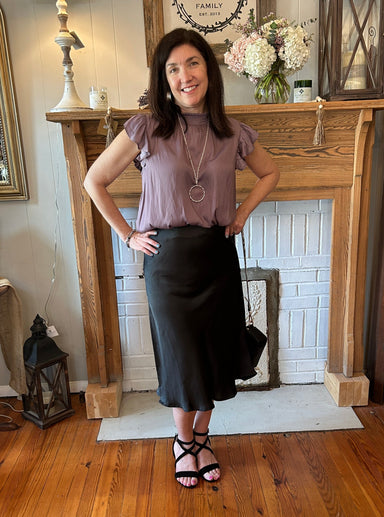 This Long Silky Midi Skirt provides a perfect balance between style and comfort. We love the versatility it offers.... Pair it with your favorite T and sneakers for a cute errand and luncheon day.  Add a knotted blouse to dress it up a a little bit... then some cute wedges or heels for an even dressier look. The fabric is silky and shimmery and feels so good. The skirt is a midi length and has an elastic waist and a side slit.
