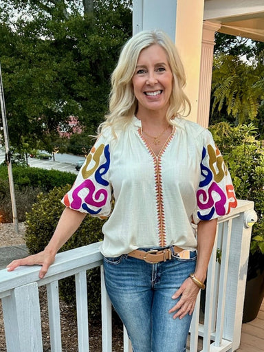You will love our ruffled collar top featuring a cream background that highlights its stunning embroidered puffed sleeves. The vibrant Fall accent colors add a warm, seasonal touch, making it perfect for stylish autumn outings. Designed to blend classic charm with eye-catching details, this top effortlessly enhances your look with a unique, feminine flair.

Cindy is wearing a size Medium. She paired it with our "Risen High Rise-Wide Baggy Jeans in Dark". She accessorized with