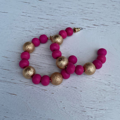 These stunning Fuchsia and Gold Glitter Beaded Earrings offer a unique combination of color and texture. Each hoop earring is crafted with fuchsia and gold glitter beads and features a post style backing. Perfect for adding a touch of sparkle to any look.