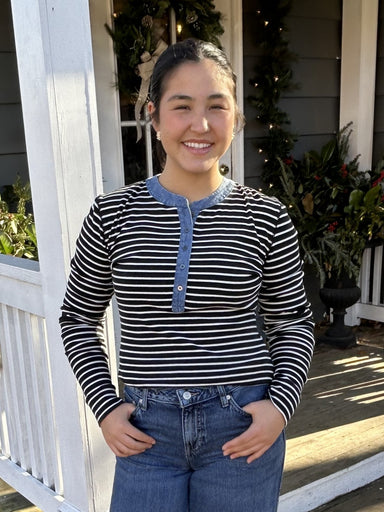This versatile henley-style top combines timeless appeal with modern flair. The classic black and white stripe design pairs effortlessly with your favorite denim or black pants, making it a go-to piece for any occasion. Fun denim trim adds a playful touch that elevates the traditional button-down silhouette. Whether you're dressing up or keeping it casual, this two-tone essential delivers style and comfort in one chic package.

Material: 90% Cotton / 10% Polyester

Care Instructions: Hand wash separately in