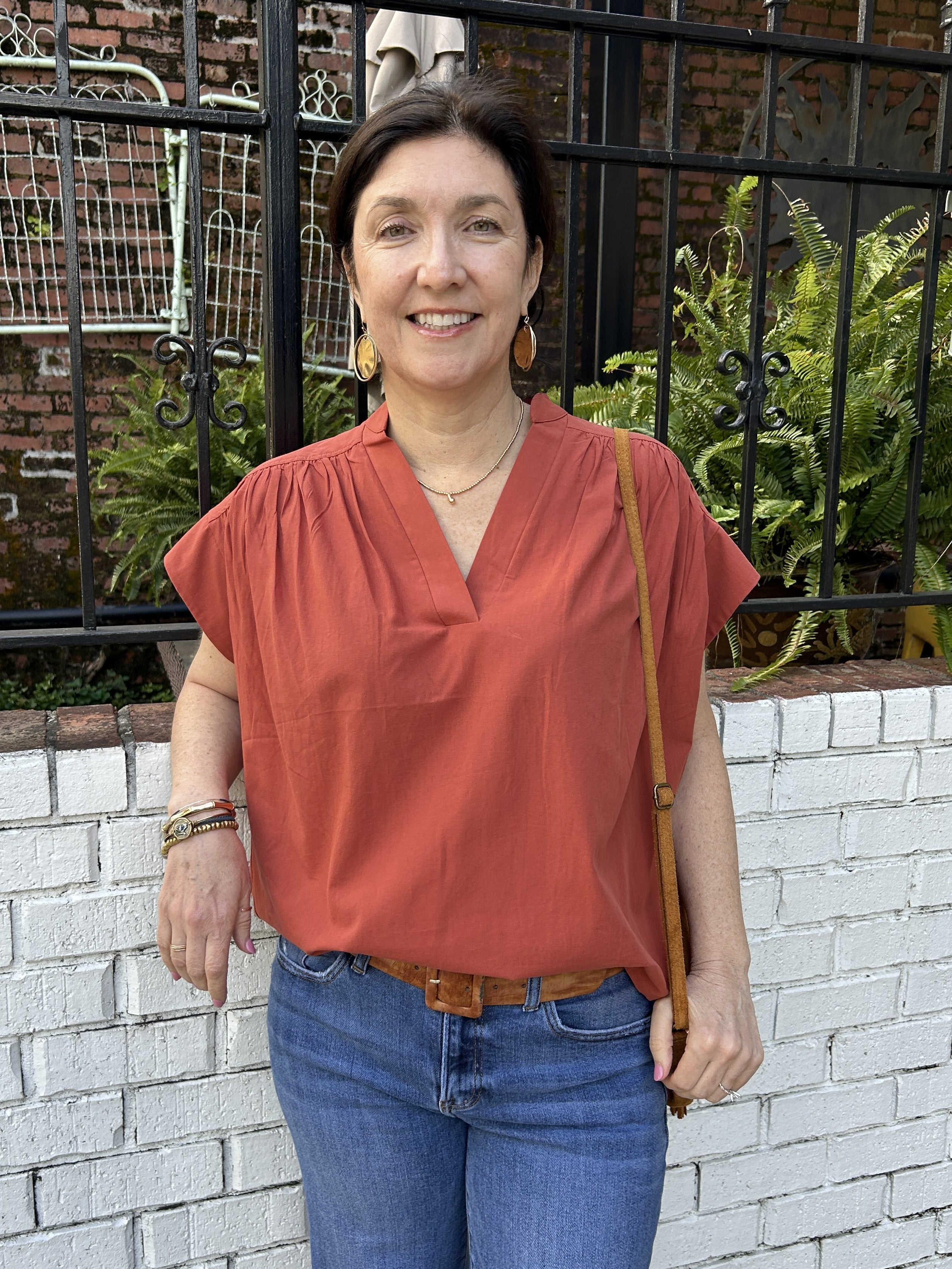 Embrace the season with this charming V-neck top in a rich rust hue, perfect for fall. Featuring delicate cap sleeves and gathered shoulders, it offers a flattering silhouette that enhances your natural shape. Lightweight and stylish, this top effortlessly combines comfort with seasonal elegance.

Tara is wearing a size Small.

Material: 100% Cotton

Care Instructions: Hand wash cold, do not tumble dry