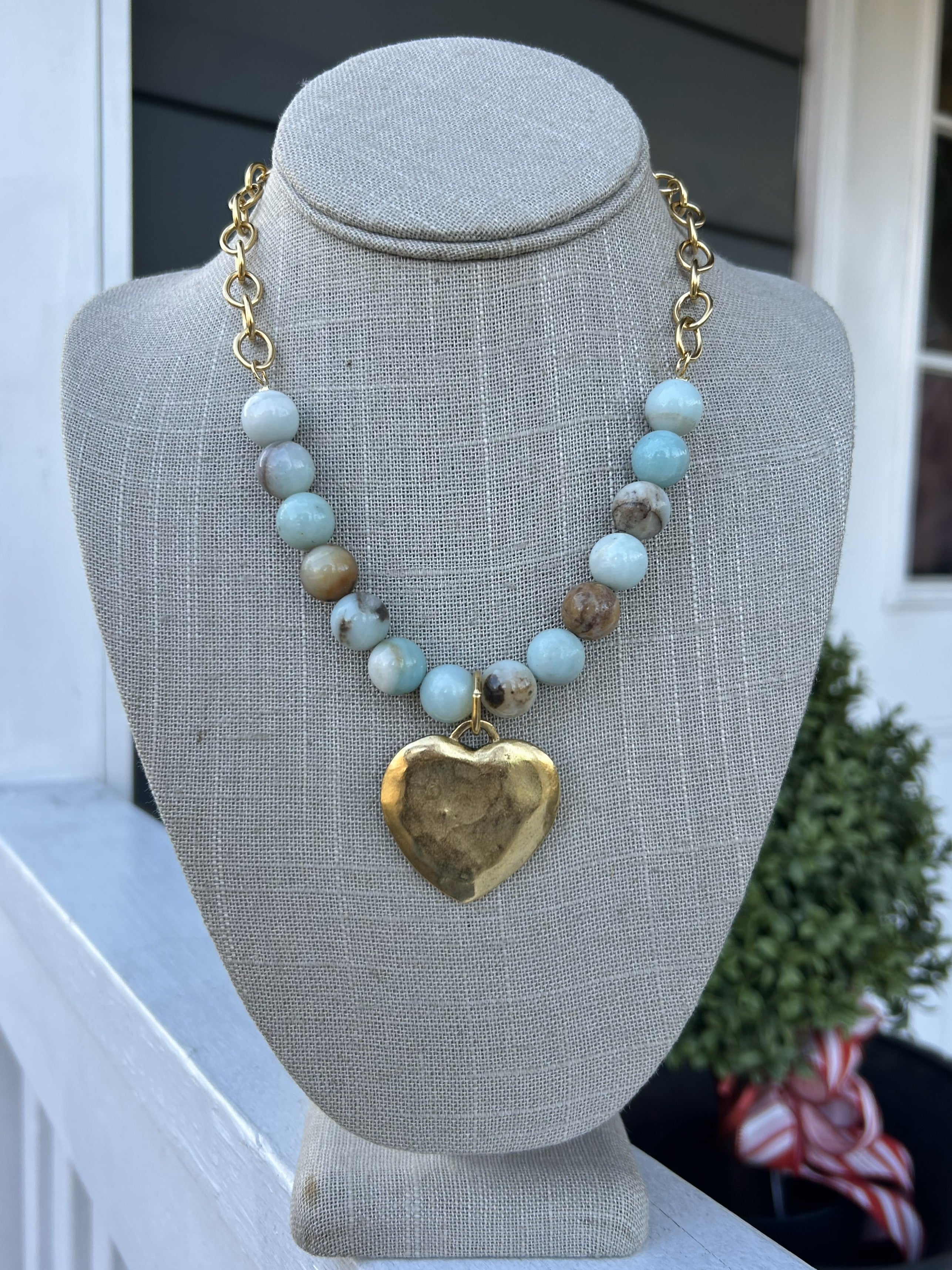 Capture hearts with this beautifully crafted necklace that balances artisanal charm with refined elegance. The striking hammered heart pendant becomes an instant focal point, while the interplay of lustrous gold chain and soft light blue and beige beads creates a soothing, cohesive aesthetic. The gentle color palette complements both casual and dressed-up looks. Perfect for expressing your individuality, this necklace combines meaningful symbolism with wearable beauty that you'll treasure for years to come.