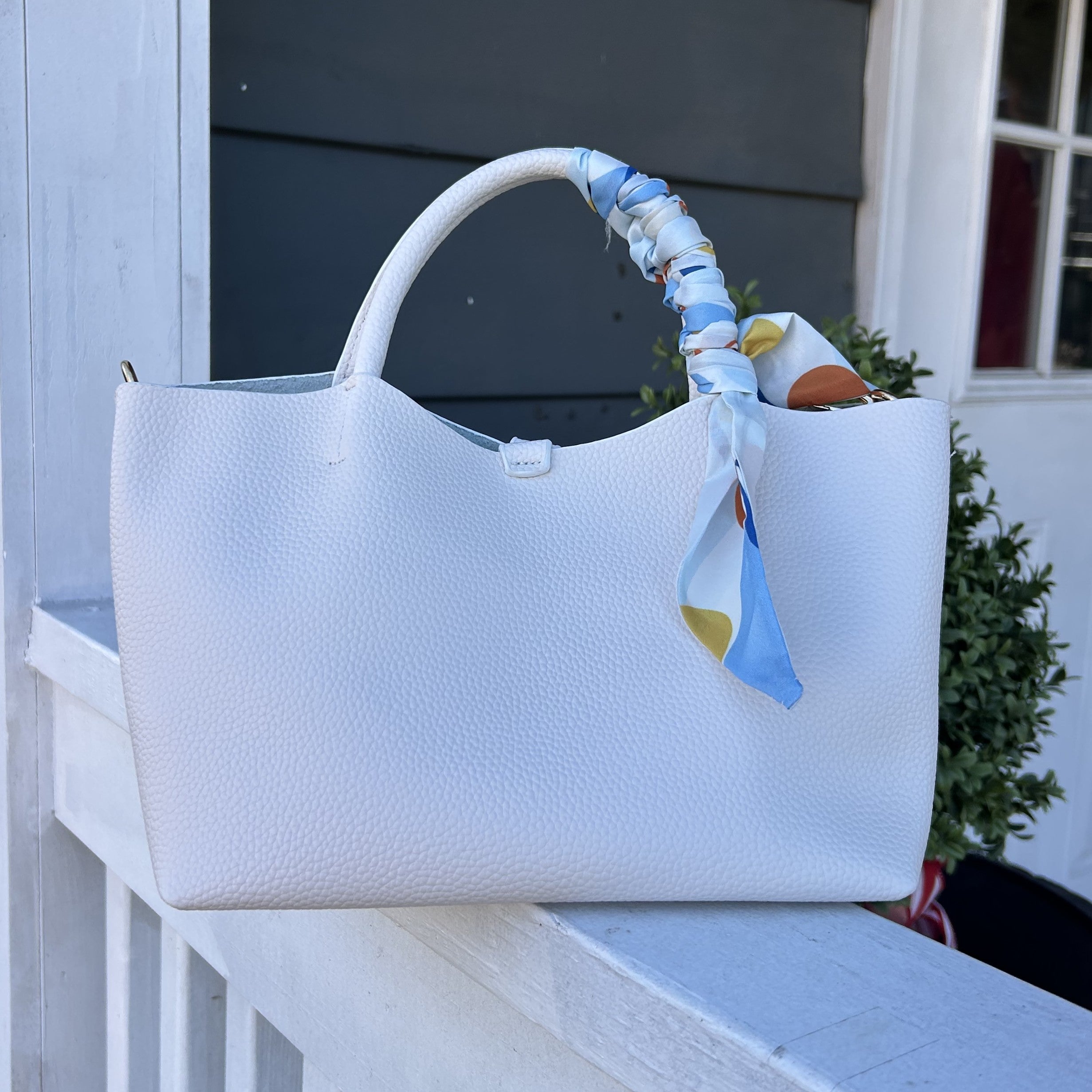 Meet the Venice Bag—where sophistication meets playful charm. This stunning vegan leather design features a textured pebbled finish that catches the light beautifully, while a vibrant scarf accent injects personality into every outfit. Designed for the modern woman, it arrives with a coordinating cosmetic bag for organized beauty essentials, plus dual carrying options: comfortable short handles for hand-carry or a cross-body strap for hands-free convenience. The magnetic closure keeps everything secure whil