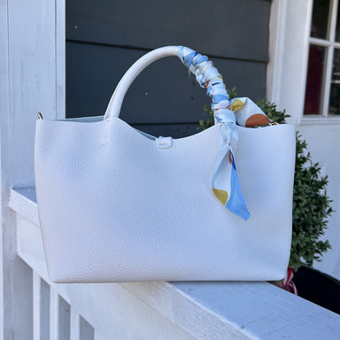 Meet the Venice Bag—where sophistication meets playful charm. This stunning vegan leather design features a textured pebbled finish that catches the light beautifully, while a vibrant scarf accent injects personality into every outfit. Designed for the modern woman, it arrives with a coordinating cosmetic bag for organized beauty essentials, plus dual carrying options: comfortable short handles for hand-carry or a cross-body strap for hands-free convenience. The magnetic closure keeps everything secure whil