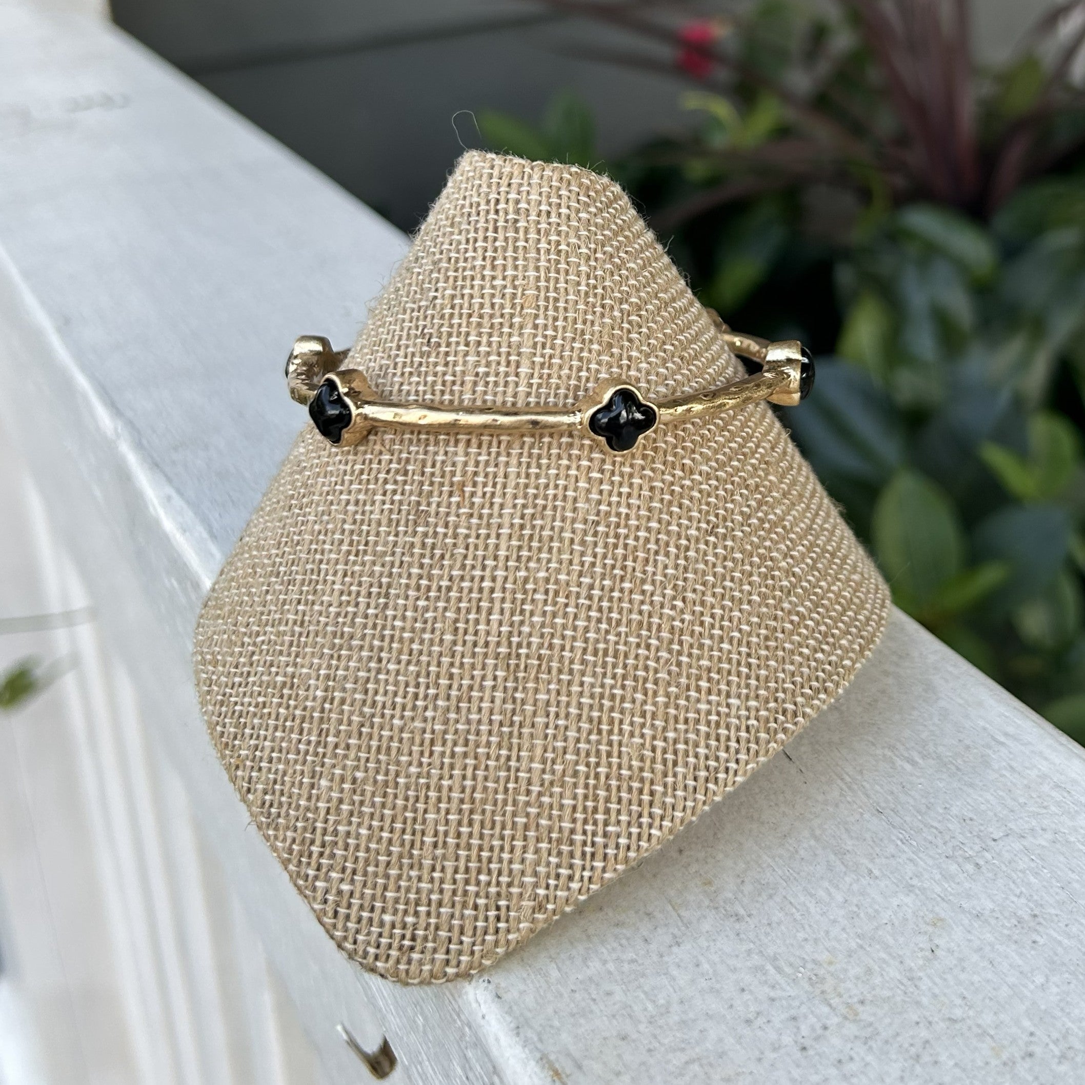 Lovely gold bangle bracelets featuring vibrant colored clover accents that effortlessly transition from casual to dressy occasions. The hammered gold hardware adds texture and sophistication, while the versatile design works beautifully worn solo or stacked for a bolder statement. A timeless piece that complements any wardrobe.