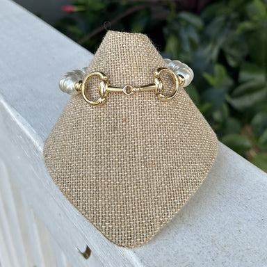 Sophisticated pearl stretch bracelet with a striking gold snaffle bit accent that brings an equestrian-inspired touch to classic elegance. The stretchy design offers effortless comfort and easy wear, while luminous pearl beads deliver timeless beauty. Versatile enough for daily styling or dressed-up occasions, this piece seamlessly transitions from casual to refined looks.