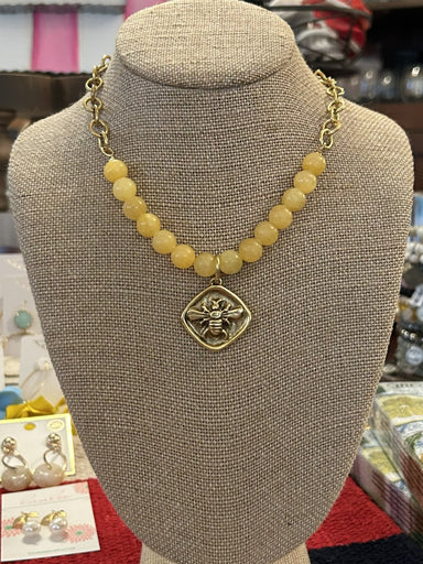 Find out what all the buzz is about! This beautiful gold chain necklace is anchored by lovely yellow beads and a bee pendant. The bee pendant has a hammered look and is diamond shaped. This is a perfect gift for the garden enthusiast, bee lover or Tech fan.

Designed and made by local artist
Approximate Length: 17-19"