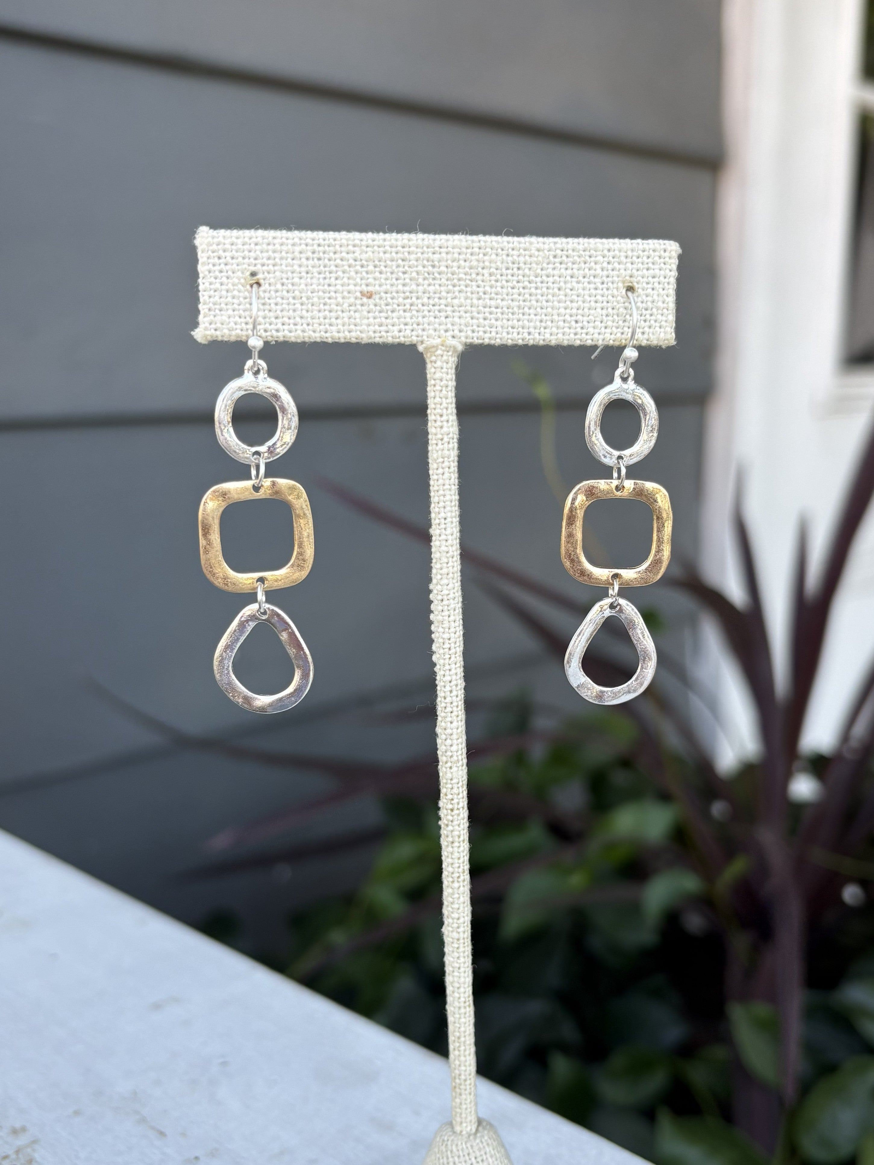 Discover the perfect balance of style and versatility with these Mixed Metal Hammered Dangle Earrings. Crafted with a beautiful blend of gold and silver, the hand-hammered texture creates depth and character that catches light from every angle. The gentle dangle movement adds grace and fluidity to your look, whether you're dressing up for a special occasion or keeping it casual. These earrings seamlessly transition between any outfit, making them an indispensable addition to your jewelry collection for thos