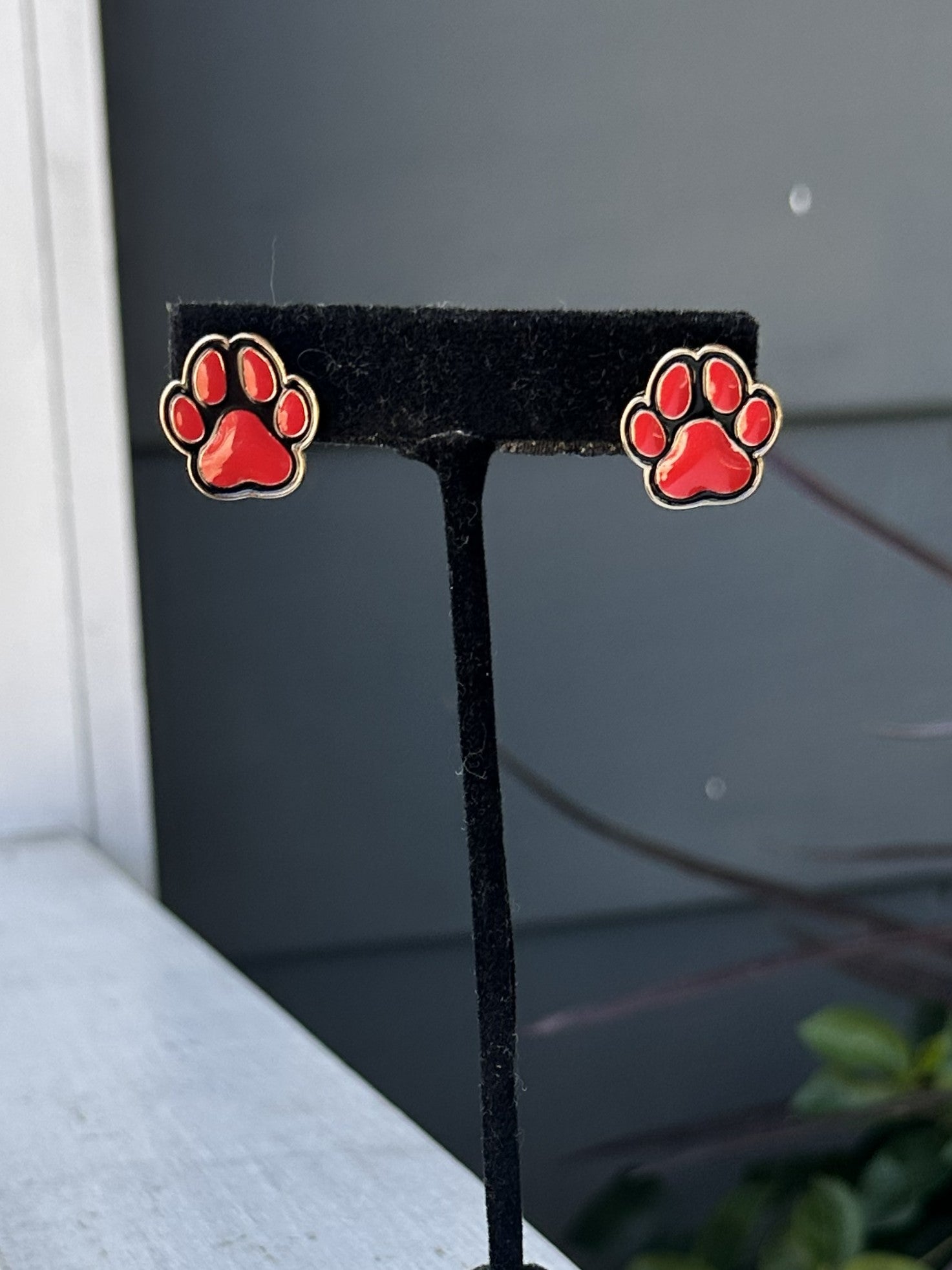Show your team spirit with these Game Day Red &amp; Black Paw Post Earrings. Featuring a charming paw print, these earrings are perfect for game day celebrations and showing your pride year-round. The classic post style offers comfortable, everyday wear while making a spirited statement. Whether you're cheering from the stands or showing support around town, these fun earrings bring playful team pride to any outfit.