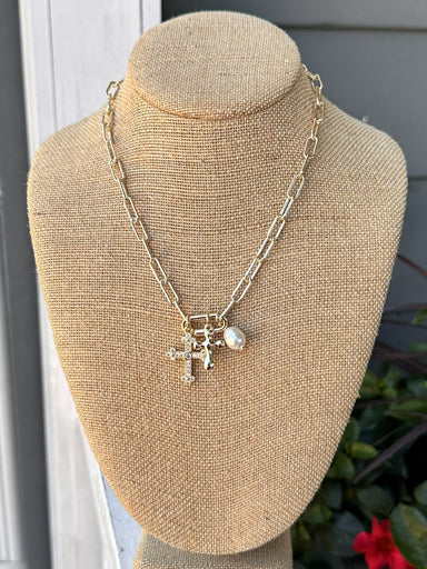 Add a touch of elegance to any outfit with our Gold Necklace w/ Cross &amp; Pearl Charms! This chain necklace features a stunning crosses and pearl charms, making it the perfect statement piece for any occasion – dressy or casual.

Approximate length: 17-19"