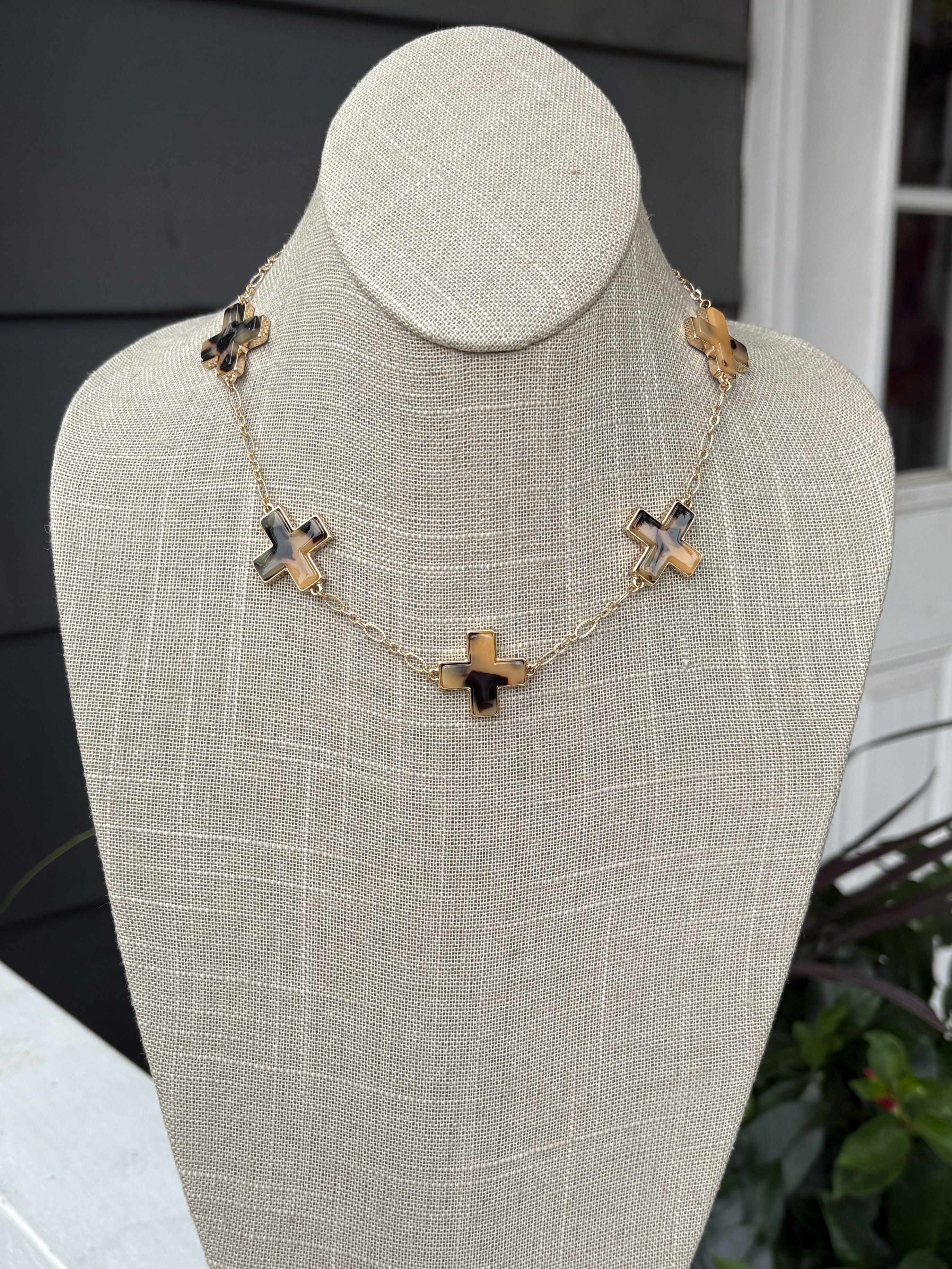 Elegant short necklace featuring cross-shaped pendants in rich tortoise tones, suspended from a gleaming gold chain. Perfect for layering or wearing solo, this versatile piece adds a touch of sophistication to any outfit. The compact length makes it ideal for everyday wear and special occasions alike.

Pair with our matching bracelet.