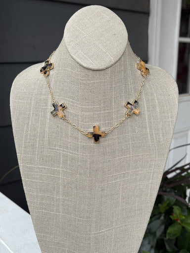 Elegant short necklace featuring cross-shaped pendants in rich tortoise tones, suspended from a gleaming gold chain. Perfect for layering or wearing solo, this versatile piece adds a touch of sophistication to any outfit. The compact length makes it ideal for everyday wear and special occasions alike.

Pair with our matching bracelet.