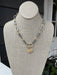 This short gray and gold chain necklace is a versatile essential for any jewelry collection. The eye-catching rhinestone-embellished lock pendant adds intrigue and glamour, while the delicate chain keeps the overall look refined. Layer it with other pieces for a curated aesthetic, or wear it alone to let the pendant shine. Perfect for transitioning from day to night.