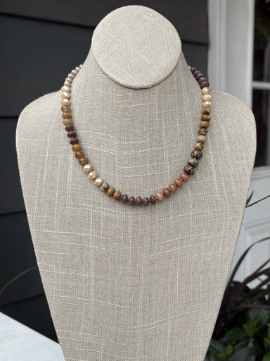 This elegant beaded necklace showcases a harmonious palette of warm brown and beige tones, expertly arranged in graduated sizes for visual interest and dimension. The thoughtfully designed shorter length makes it ideal for layering with other pieces or wearing as a standalone statement. Each bead is selected to create a cohesive, sophisticated look that works beautifully with any skin tone. Perfect for adding warmth and texture to both casual and dressed-up outfits, this versatile piece is a timeless additi