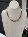 This elegant beaded necklace showcases a harmonious palette of warm brown and beige tones, expertly arranged in graduated sizes for visual interest and dimension. The thoughtfully designed shorter length makes it ideal for layering with other pieces or wearing as a standalone statement. Each bead is selected to create a cohesive, sophisticated look that works beautifully with any skin tone. Perfect for adding warmth and texture to both casual and dressed-up outfits, this versatile piece is a timeless additi