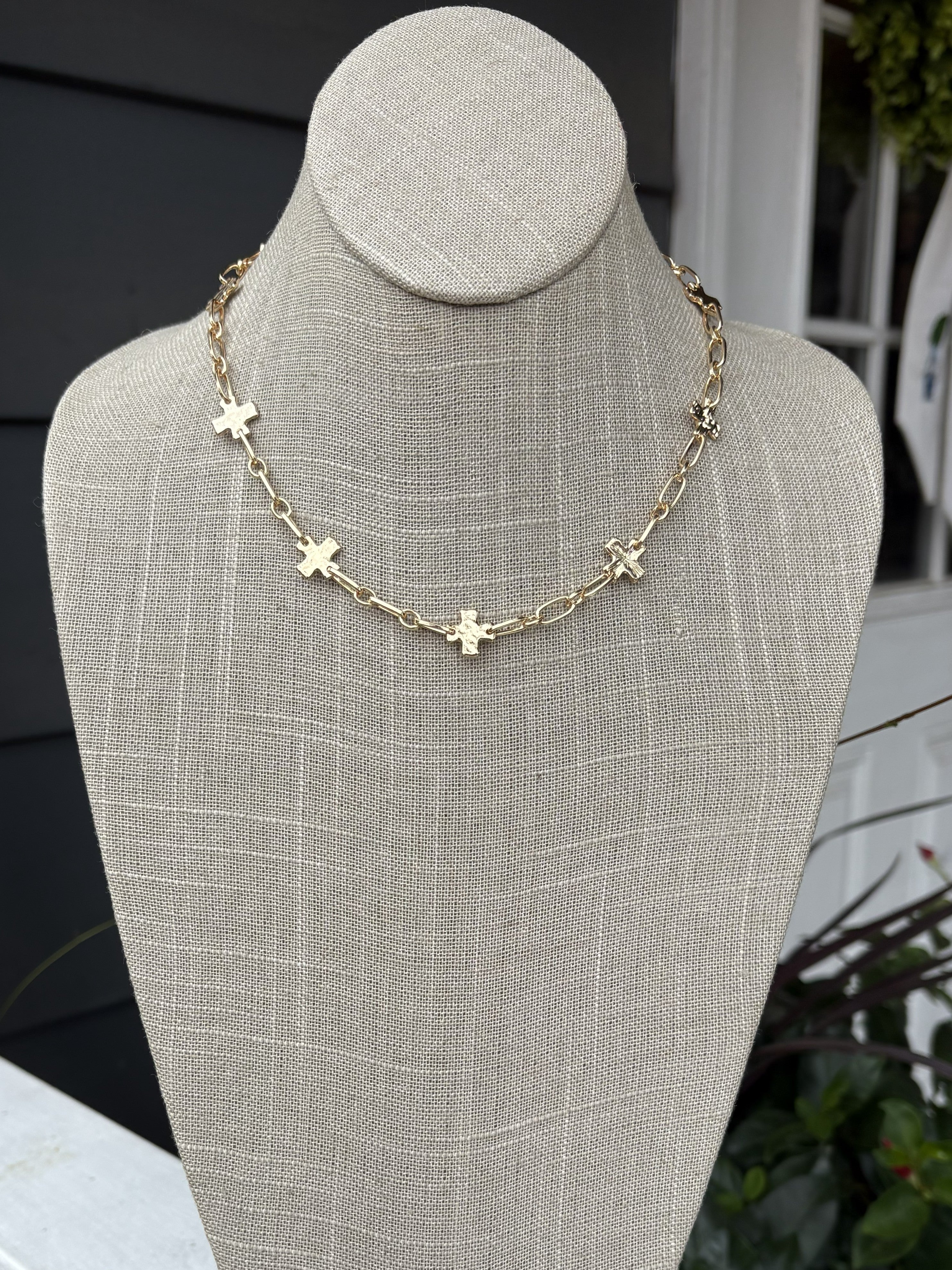 Delicate gold chain adorned with textured gold crosses creates an understated yet sophisticated look. Perfect for layering or wearing alone, this necklace combines minimalist design with timeless elegance. The short length offers versatile styling options for any occasion.