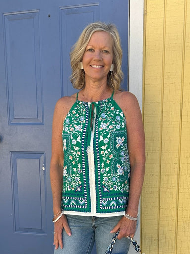 This charming sleeveless top combines feminine details with everyday versatility. The striking green and navy floral border print adds visual interest, while the tied spaghetti straps and front button closure create an effortlessly put-together look. Fully lined for comfort and structure, it pairs beautifully with jeans, skirts, or trousers. Perfect for spring and summer styling, this piece works equally well dressed down or elevated for special occasions.

Material: 70% Rayon / 30% Linen; Lining: 95% Polye