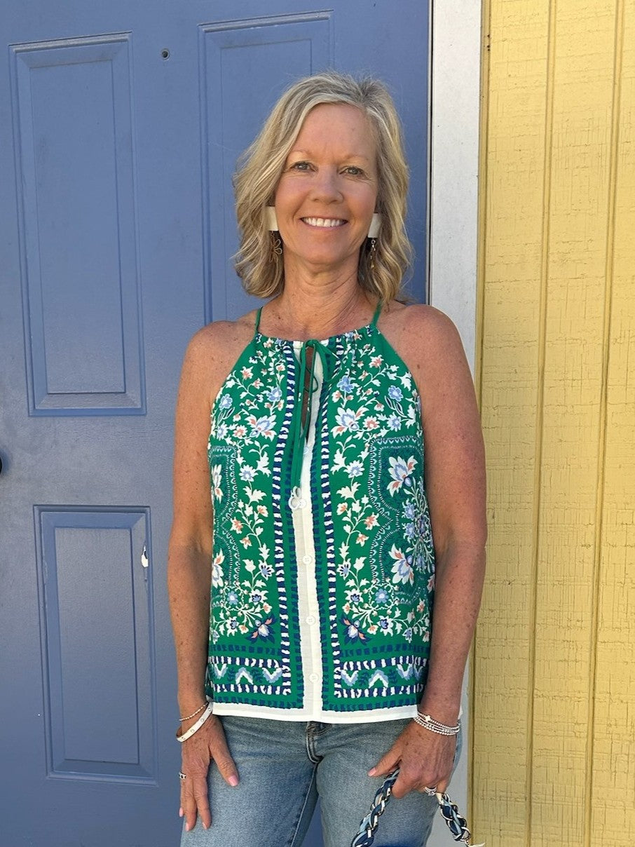This charming sleeveless top combines feminine details with everyday versatility. The striking green and navy floral border print adds visual interest, while the tied spaghetti straps and front button closure create an effortlessly put-together look. Fully lined for comfort and structure, it pairs beautifully with jeans, skirts, or trousers. Perfect for spring and summer styling, this piece works equally well dressed down or elevated for special occasions.

Material: 70% Rayon / 30% Linen; Lining: 95% Polye