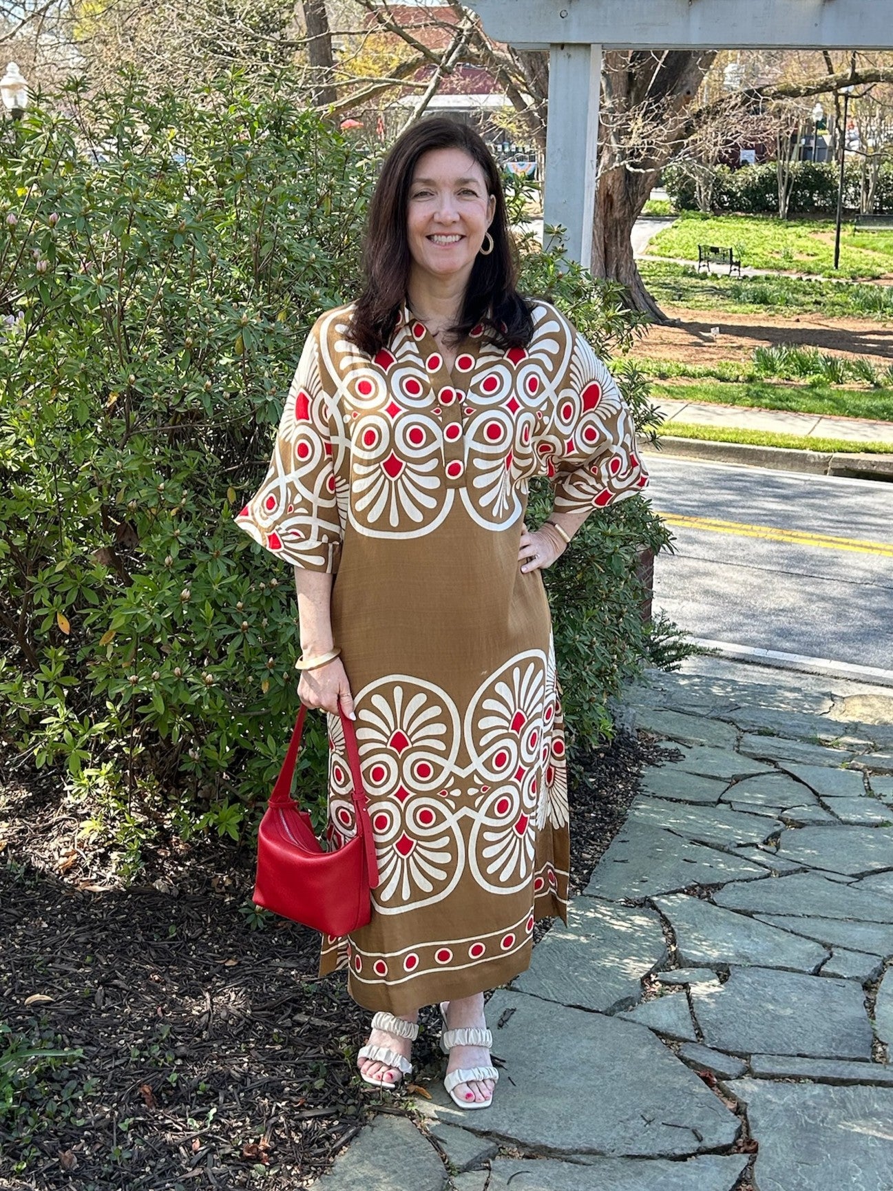 This stunning midi dress showcases a warm mustard foundation with striking geometric patterns in red and cream, creating visual interest from every angle. The V-neck collar adds a touch of sophistication to its relaxed, bohemian charm. Crafted from airy, lightweight fabric that drapes gracefully, it's ideal for warm-weather adventures, or weekend gatherings.