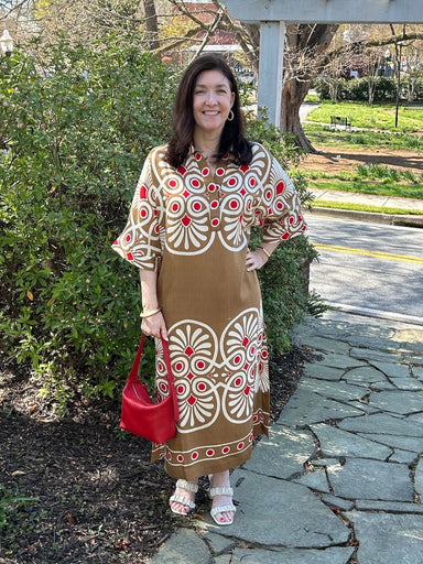 This stunning midi dress showcases a warm mustard foundation with striking geometric patterns in red and cream, creating visual interest from every angle. The V-neck collar adds a touch of sophistication to its relaxed, bohemian charm. Crafted from airy, lightweight fabric that drapes gracefully, it's ideal for warm-weather adventures, or weekend gatherings.