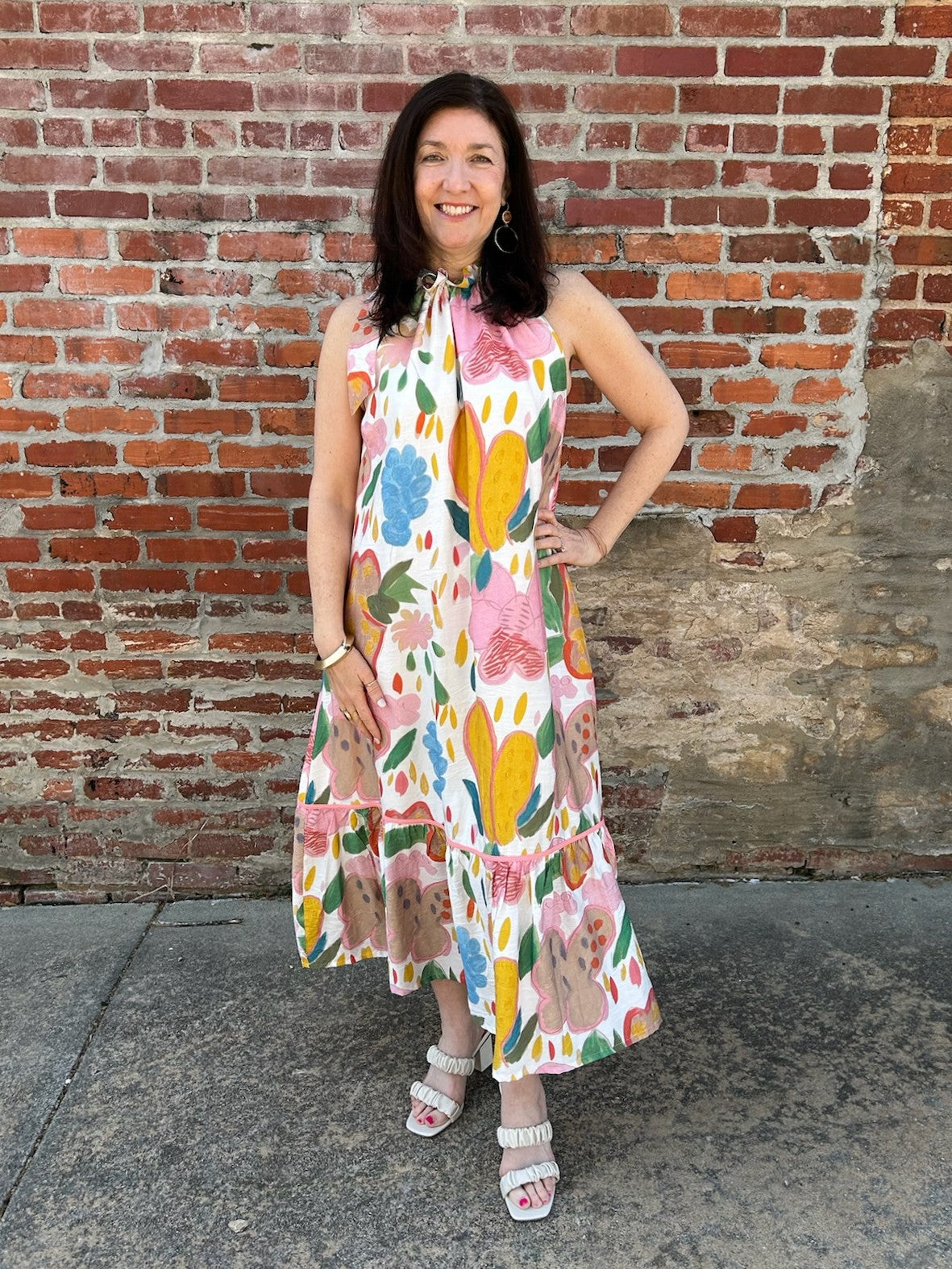 This stunning sleeveless midi dress combines artistic style with everyday wearability. Its captivating abstract floral design blooms across a creamy canvas in rich, complementary hues that draw the eye. The adjustable tie detail at the neckline offers a customizable fit, while the layered tiered skirt provides flattering silhouette and effortless movement. Fully lined for a polished feel, this versatile piece transitions seamlessly from brunch to evening gatherings.

Material: 85% Rayon / 15% Nylon; Lining: