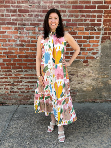 This stunning sleeveless midi dress combines artistic style with everyday wearability. Its captivating abstract floral design blooms across a creamy canvas in rich, complementary hues that draw the eye. The adjustable tie detail at the neckline offers a customizable fit, while the layered tiered skirt provides flattering silhouette and effortless movement. Fully lined for a polished feel, this versatile piece transitions seamlessly from brunch to evening gatherings.

Material: 85% Rayon / 15% Nylon; Lining: