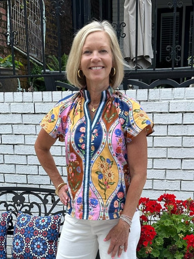 Brighten your summer wardrobe with this cheerful floral top, featuring a striking striped placket that adds visual interest to the front. Short sleeves keep you cool and comfortable, while the vibrant color palette brings playful energy to any outfit. Style it effortlessly with white denim shorts or a white flowing skirt for an instant seasonal look that feels fresh and put-together.

Barbara is wearing a size XSmall.

Material: 100% Cotton

Care Instructions: Hand wash cold, dry flat