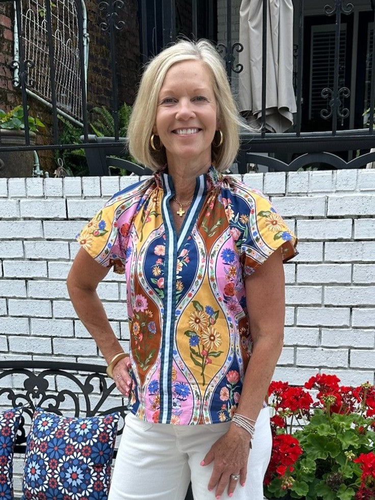 Brighten your summer wardrobe with this cheerful floral top, featuring a striking striped placket that adds visual interest to the front. Short sleeves keep you cool and comfortable, while the vibrant color palette brings playful energy to any outfit. Style it effortlessly with white denim shorts or a white flowing skirt for an instant seasonal look that feels fresh and put-together.

Barbara is wearing a size XSmall.

Material: 100% Cotton

Care Instructions: Hand wash cold, dry flat