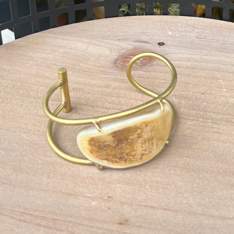 We love the style of our Brass Cuff Bracelet! This wired cuff features brass hardware and a light horn accent, adding a touch of Boho to any outfit. Perfect for both casual and dressy occasions, this bracelet is a must-have for anyone seeking a versatile and chic accessory.