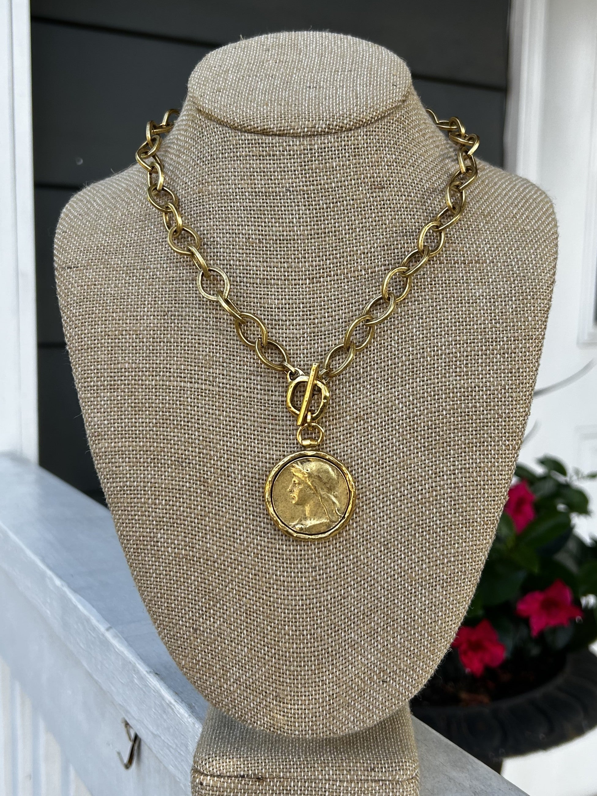 Introducing our new, unique Oval Chain Necklace featuring a stunning coin pendant. The beautiful gold chain with T-bar closure creates a luxurious foundation for the coin pendant. Perfect for adding a touch of bold elegance to any outfit.

Approximate length: 19"