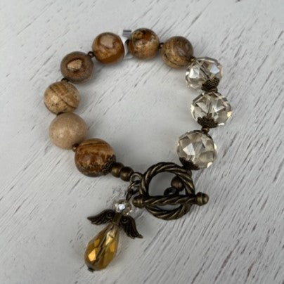 This beautiful Earth Tone & Crystal Beaded Bracelet w/ Angel Charm will help you express your faith in an elegant and stylish way. Featuring a T-bar closure, antique gold accents, and a crystal angel, it adds a sophisticated touch to any outfit. Its combination of brown earth tones and crystal beads creates an eye-catching shimmer that will surely turn heads!