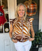 We love the zebra print, the colors, the fabric and the ribbon detailing on this Smocked Mock Neck Top! With a ruffle cap sleeve and warm colors, it's the perfect transition top for your fall wardrobe. Pair it with white denim on our warmer fall days, then move to brown pants or denim and add a jacket when the temps get cooler. It has a ruffled, mock neck with a two-button back closure. The fabric feels soft and silky.  Material: 100% Polyester  Care Instructions: Hand wash cold, flat dry