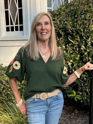 Dark green textured fabric with a striking V-neck design and unique stitched floral sleeve accents. This versatile transition piece effortlessly offers both style and comfort for season-to-season wear.