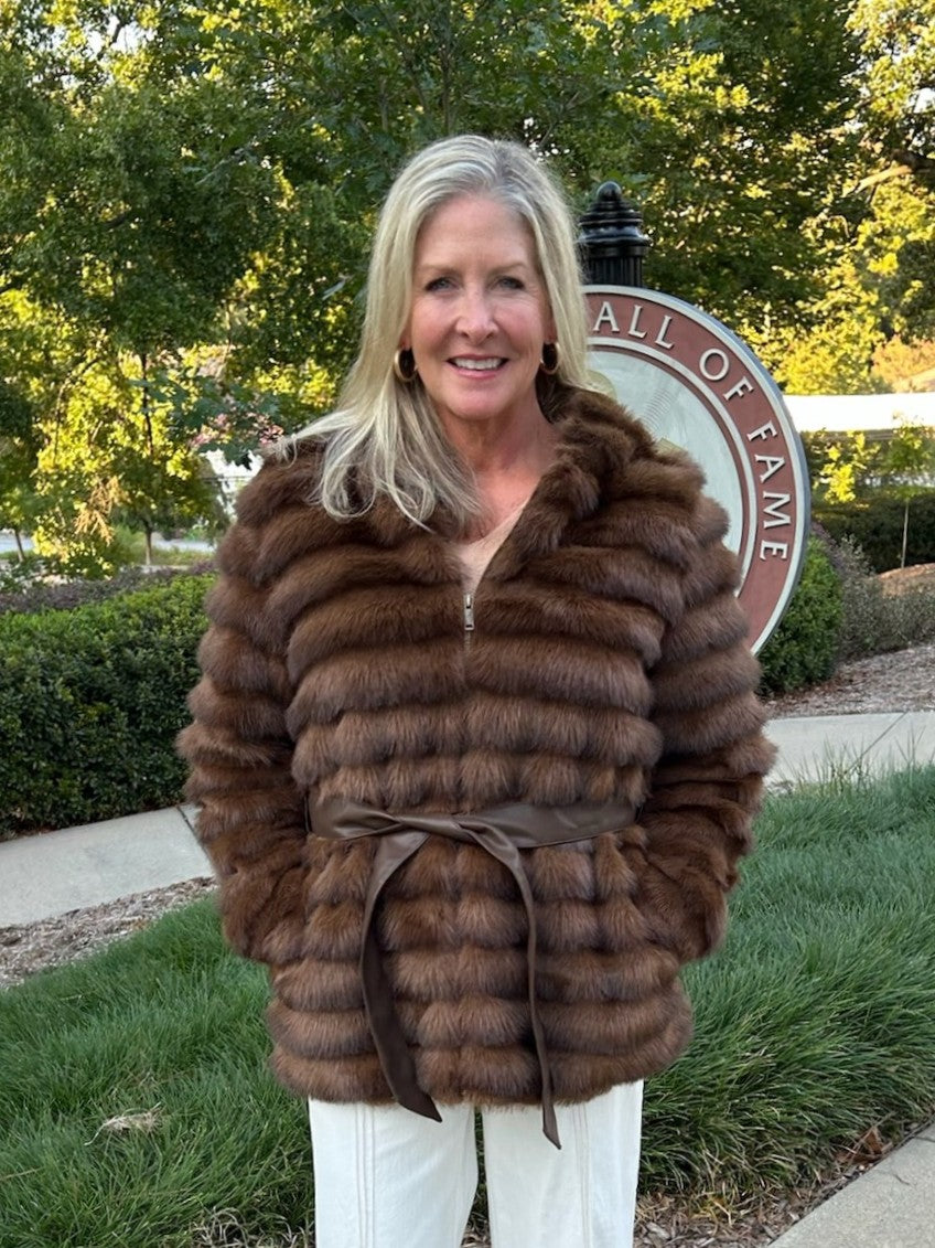 Luxurious faux fur hooded zip-up coat in a gorgeous deep brown. Features a playful oversized hoodie and faux leather tie belt that cinches at the front or back for versatile styling. The perfect layer for transitional weather—dress it up over a skirt or wear it casual with jeans. Premium craftsmanship meets effortless wearability.