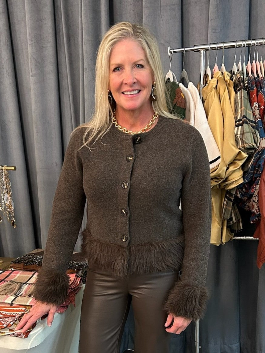 A cozy button-down sweater elevated with luxurious faux fur detailing at the wrists and waist. Versatile enough to pair with tailored pants for a polished look or dress up with a coordinating skirt and gold accessories for a night out. The soft fur trim adds texture and visual interest while keeping the overall style effortlessly chic and wearable.