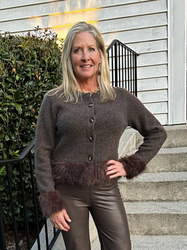A cozy button-down sweater elevated with luxurious faux fur detailing at the wrists and waist. Versatile enough to pair with tailored pants for a polished look or dress up with a coordinating skirt and gold accessories for a night out. The soft fur trim adds texture and visual interest while keeping the overall style effortlessly chic and wearable.