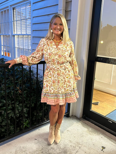 You will love this Border Print Shirt Dress. Crafted on a soft cream foundation, the eye-catching multi-color border print adds visual interest without overwhelming the silhouette. The structured button-front design pairs beautifully with a flattering V-neckline, while long sleeves provide coverage and elegance. An elastic and belted waist defines your shape and offers adjustable comfort throughout the day. Fully lined for a refined finish, this short dress works beautifully dressed up with heels or kept ca
