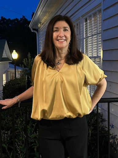 Luxurious satin fabric with a lustrous finish catches the light beautifully. Short sleeves and a flattering V-neckline create an elegant silhouette perfect for holiday gatherings and special occasions. The rich gold hue pairs effortlessly with black pants or skirts for a sophisticated, polished look.