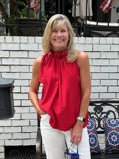 Carolee is wearing a small in this fun red top that ties on one shoulder. She has on white Risen jeans and is sporting a flag bag. 
