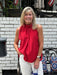 Carolee is wearing a small in this fun red top that ties on one shoulder. She has on white Risen jeans and is sporting a flag bag. 